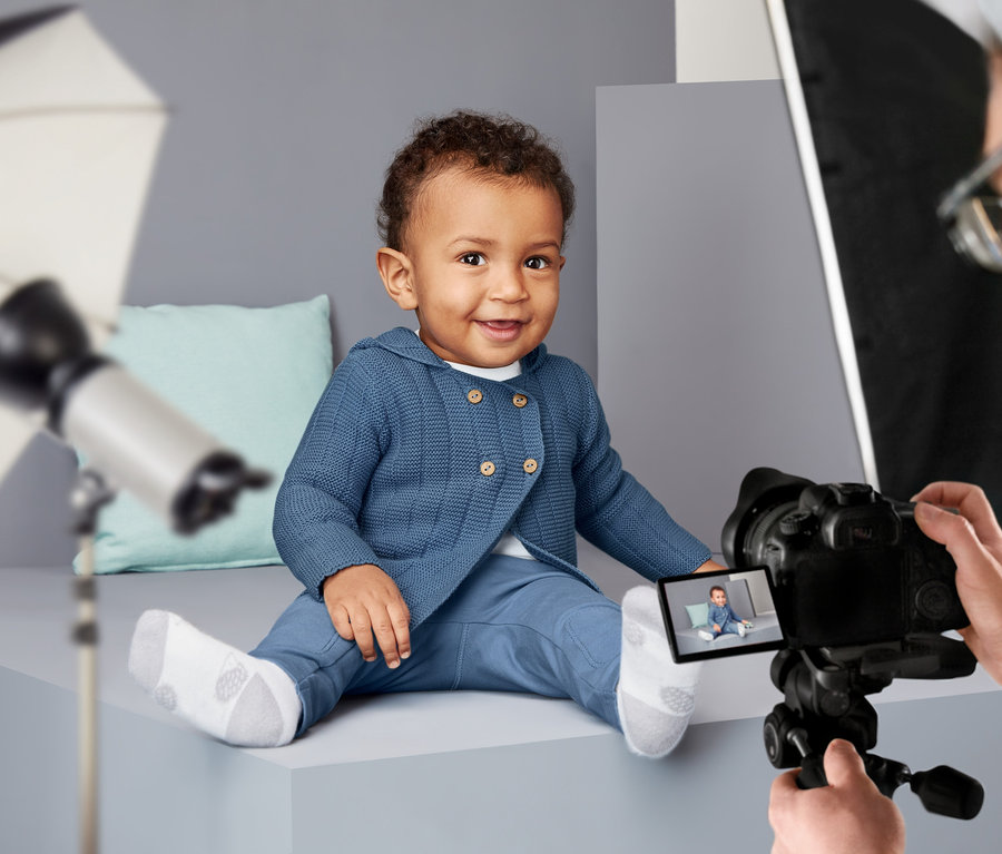 Un bébé souriant est assis et pose en jaquette en maille.