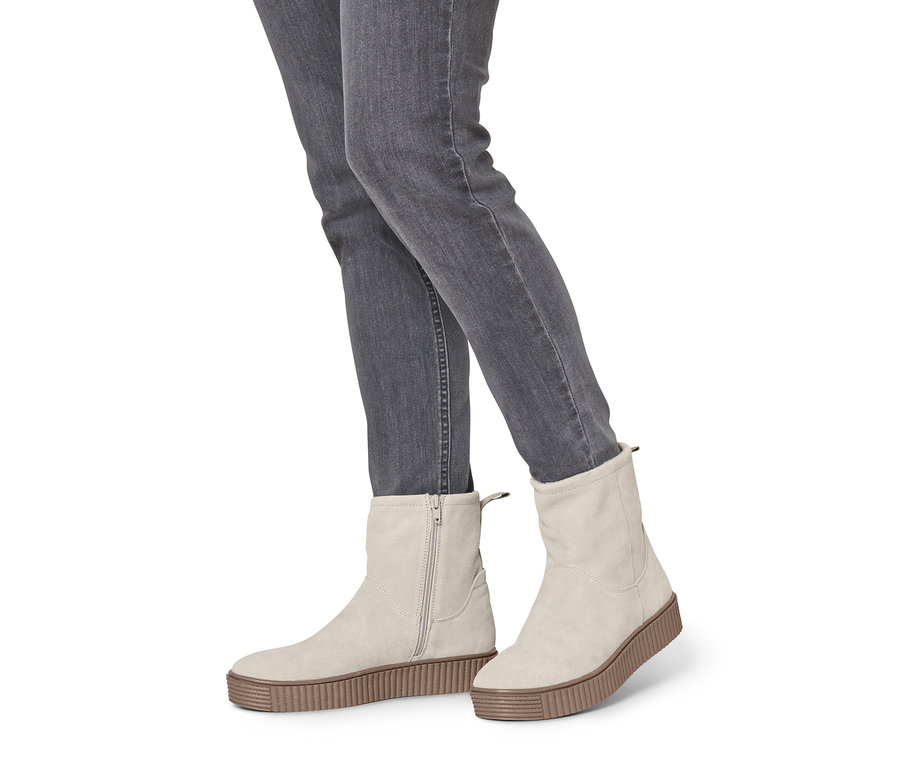 Jambes en jean gris portant des bottines beiges en cuir velours.