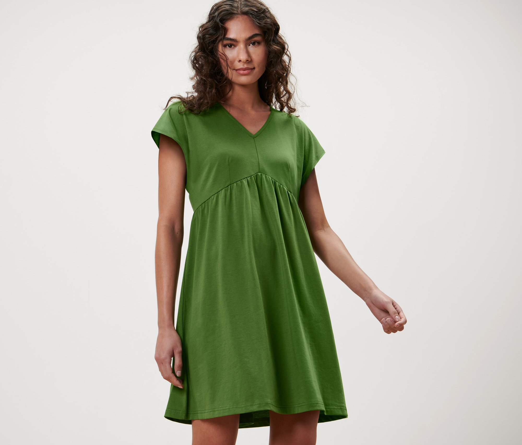 Femme posant dans une robe en jersey verte.
