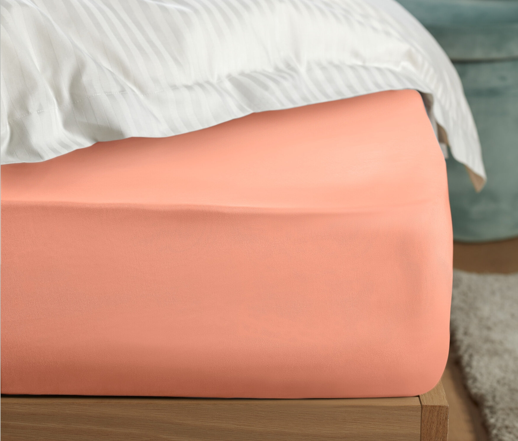 Vue détaillée d'un lit avec un drap-housse en percale abricot de taille standard et du linge de lit blanc.