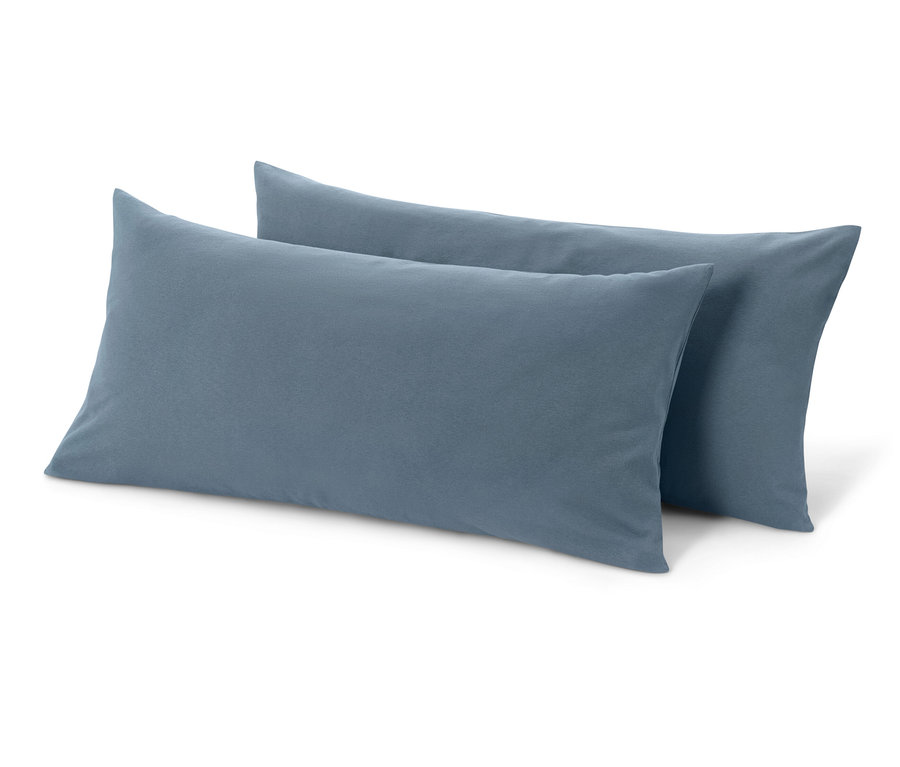 Deux taies d'oreiller en jersey bleu sont posées sur un fond blanc.
