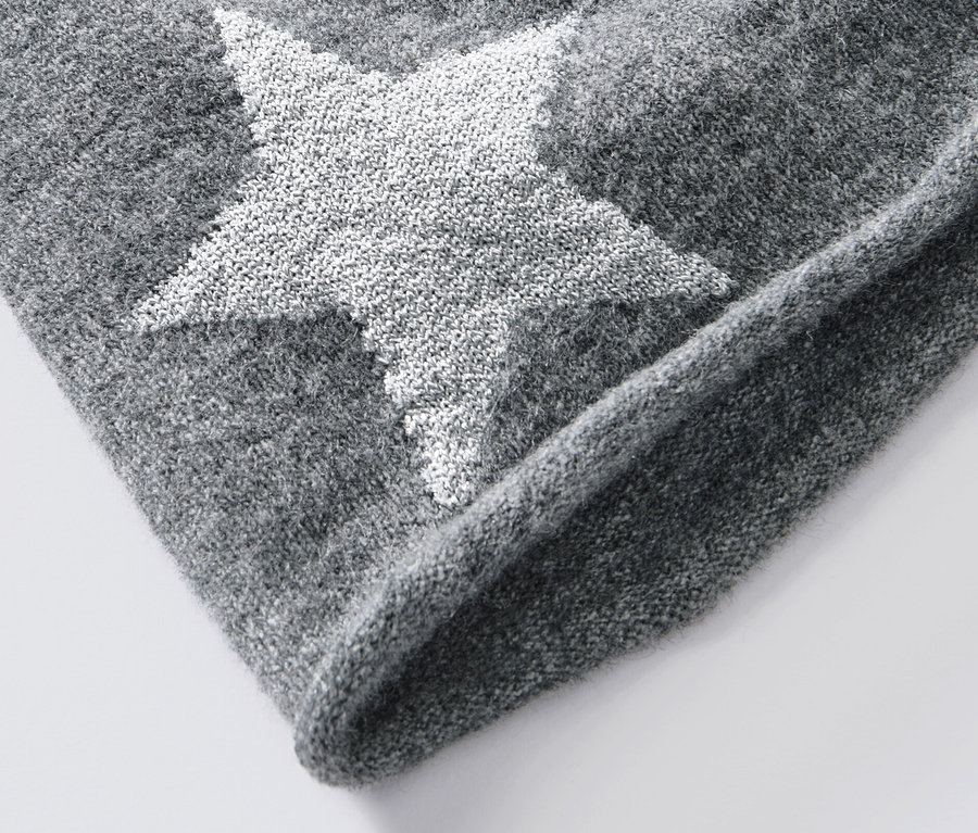 Gros plan sur un beanie en maille fine gris avec une étoile scintillante.