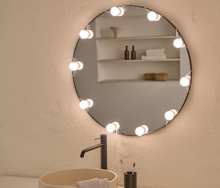 Salle de bain avec lavabo, robinet et miroir rond avec guirlande lumineuse USB à LED.