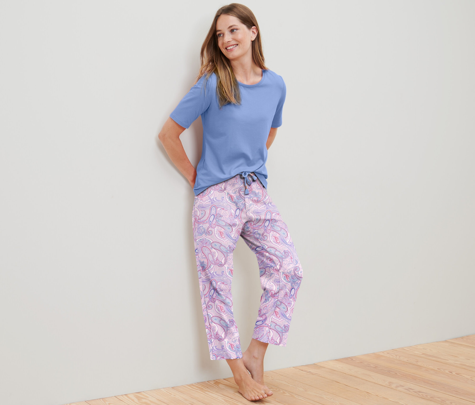 Une femme appuyée contre un mur porte un ensemble pyjama 7/8.