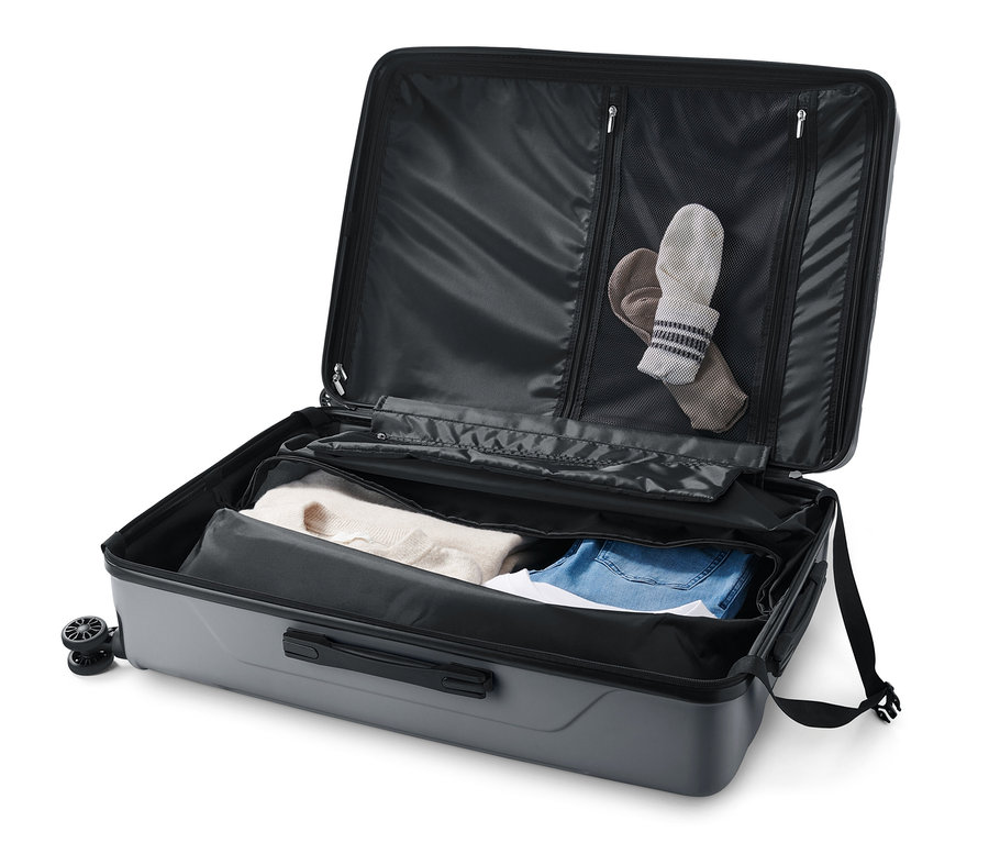 Valise rigide ouverte, grande taille, recyclée, avec des vêtements à l'intérieur.