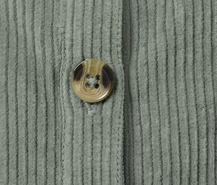Gros plan sur une salopette en velours pour bébé avec un bouton fermé.