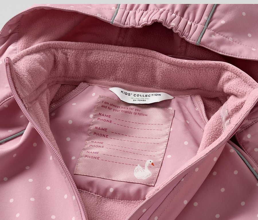 Gros plan sur une combinaison en softshell rose à pois blancs pour enfant.