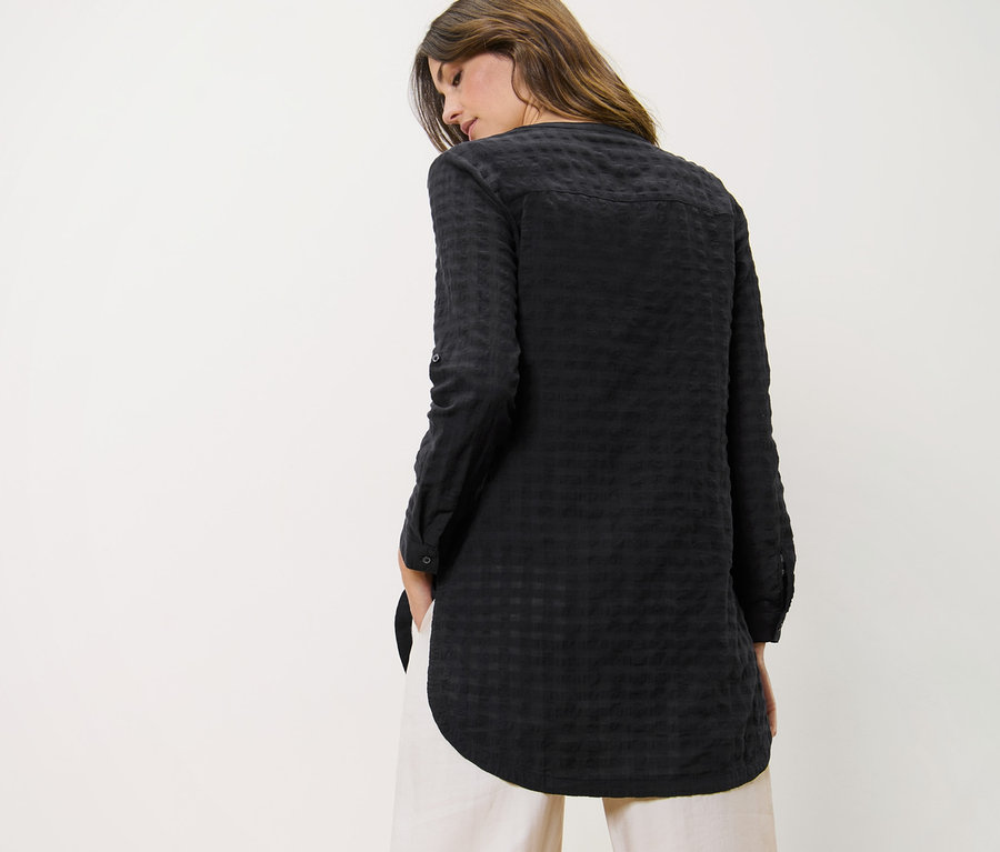 Femme portant une tunique longue à structure tissée et un pantalon.