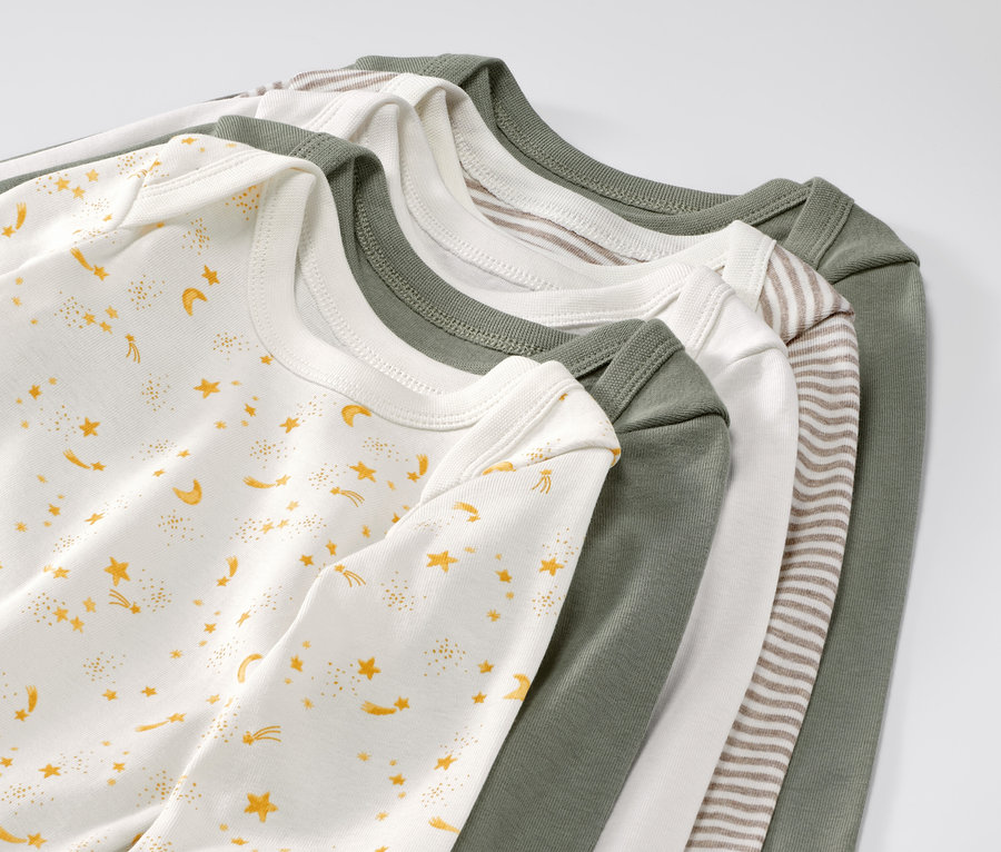 Cinq bodies évolutifs pour bébé avec des étoiles sont posés les uns sur les autres.