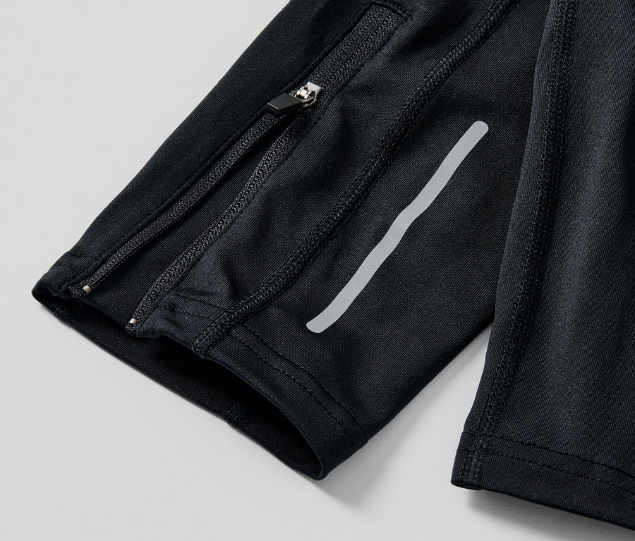 Gros plan sur un legging de sport noir avec fermeture éclair et bande réfléchissante.