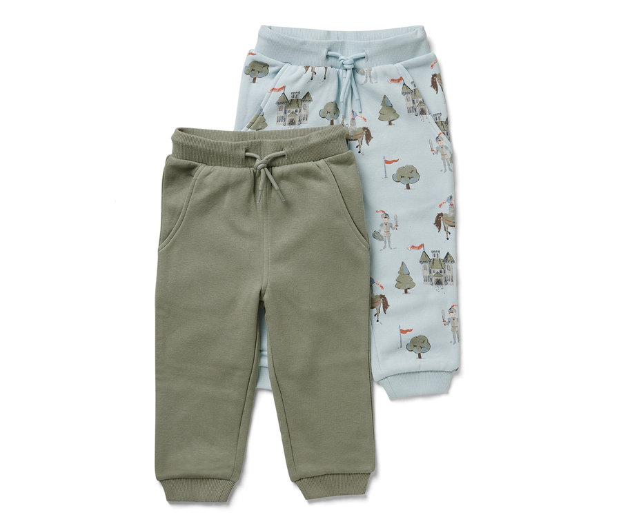 Deux pantalons de survêtement pour bébé : un vert olive et un bleu clair avec des motifs de chevaliers, de châteaux et d’arbres.