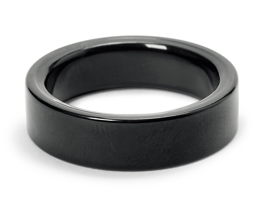 Gros plan d'une bague noire brillante sur fond blanc.