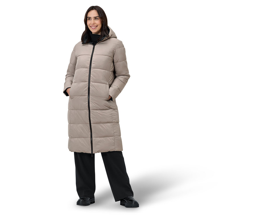 Femme posant dans un manteau en duvet beige et un pantalon noir.