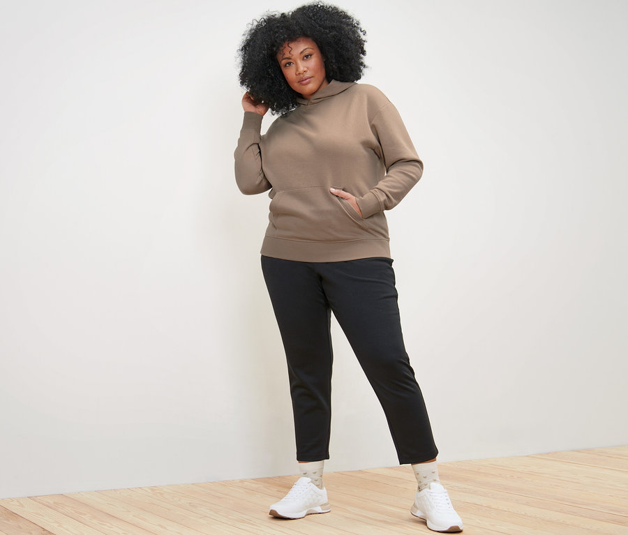 Femme posant en sweat à capuche beige.