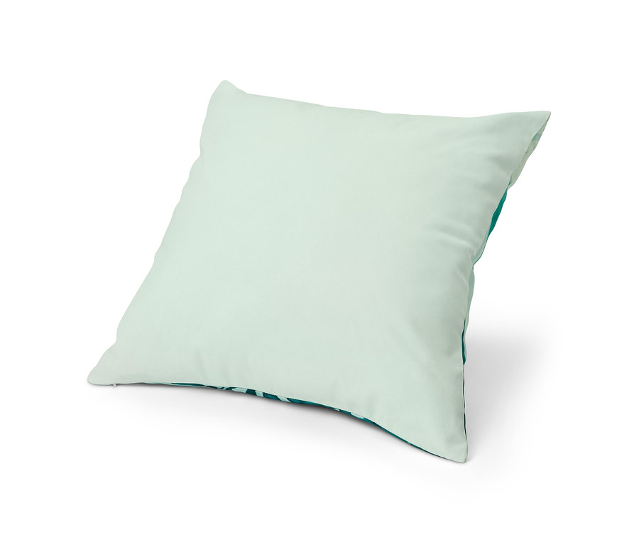 Une housse de coussin décoratif vert clair posée sur un fond blanc.