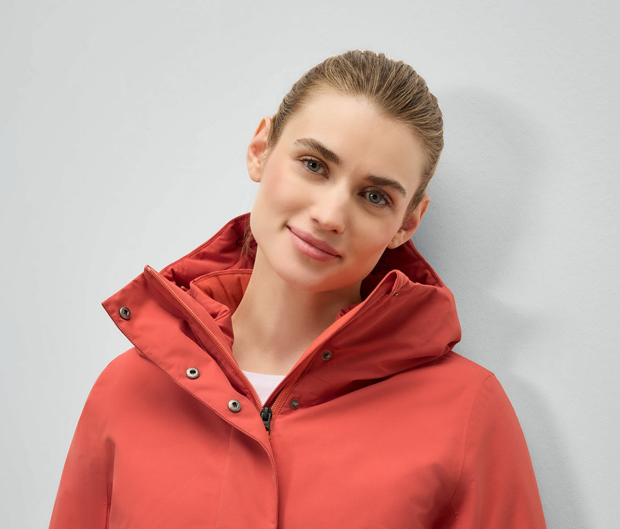 Portrait d'une femme portant une veste corail à capuche.