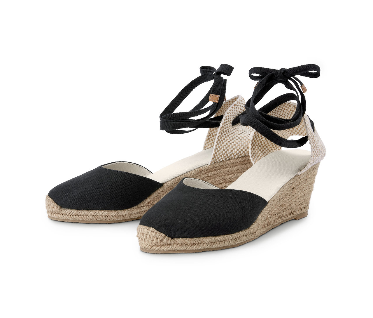 Deux espadrilles à talon compensé. Elles ont des bouts en tissu noir et des compensées beiges en cordes.
