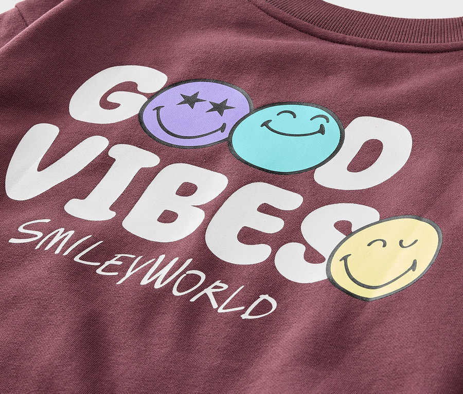 Détail d'un sweat-shirt bordeaux pour enfant SMILEYWORLD® avec intérieur gratté, imprimé GOOD VIBES et trois smileys.