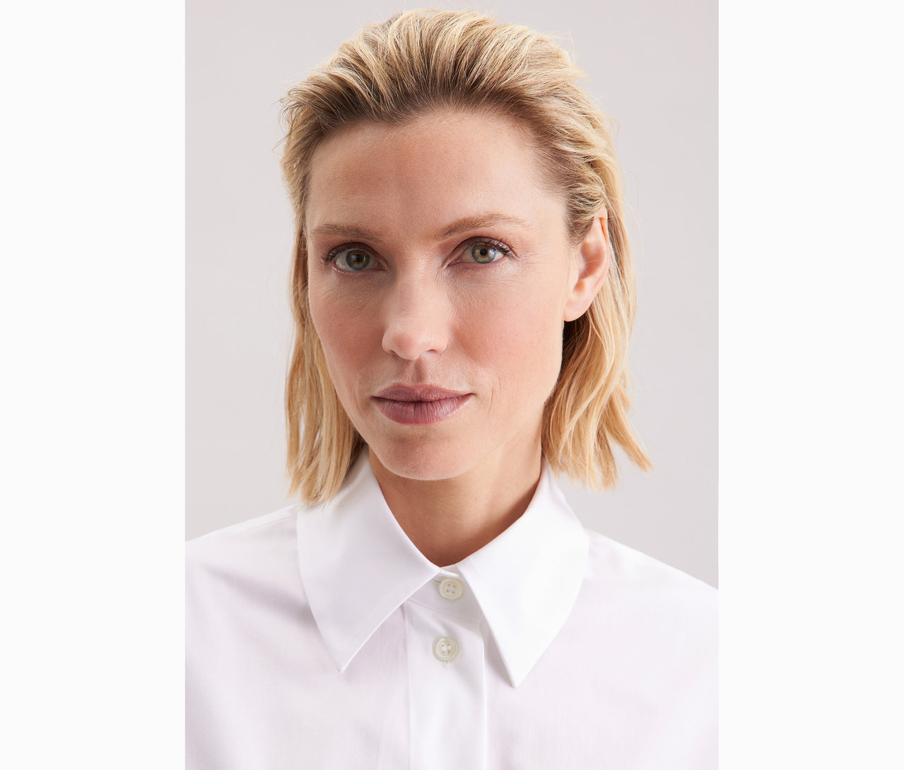 Portrait d'une femme aux cheveux blonds ondulés portant une blouse-chemise blanche grande taille Seidensticker.