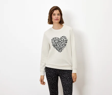 Une femme porte un sweat-shirt blanc avec un cœur à imprimé animal et un legging à imprimé animal.