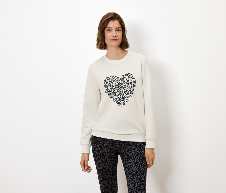 Une femme porte un sweat-shirt blanc avec un cœur à imprimé animal et un legging à imprimé animal.