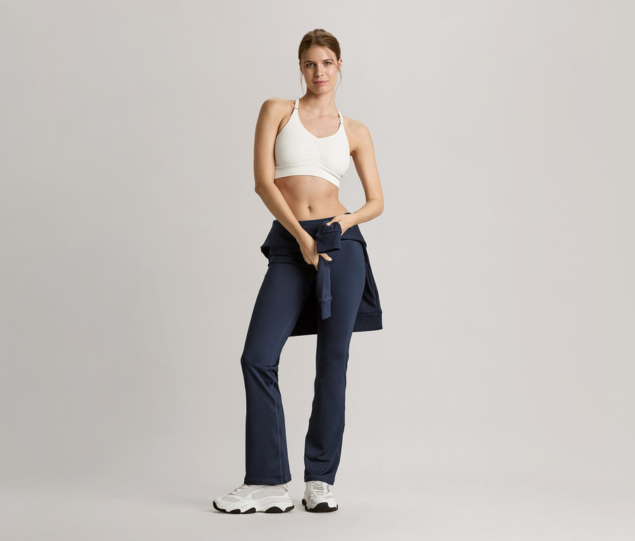Femme en tenue de sport posant avec une veste de survêtement bleu marine.