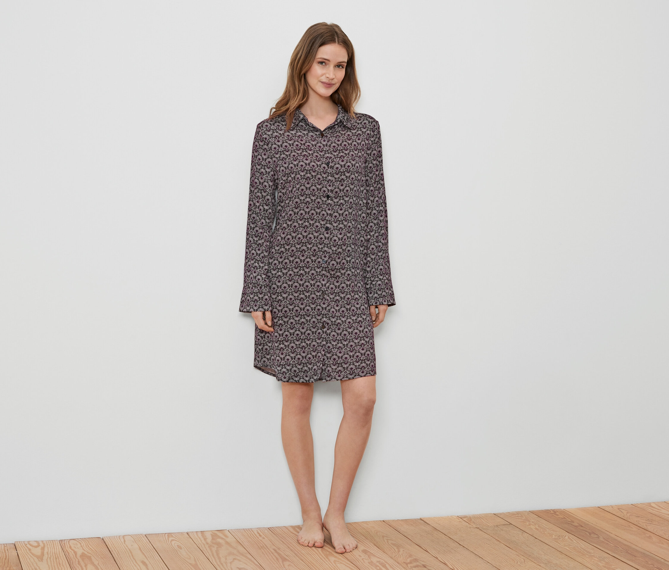 Une femme debout porte une chemise de nuit à motifs.