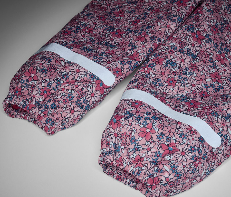 Détail d'un pantalon de pluie thermique pour enfant à motif floral avec bandes réfléchissantes.