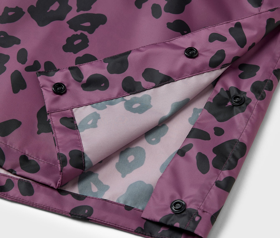 Détail d'une veste violette avec un motif animalier noir et des boutons noirs.
