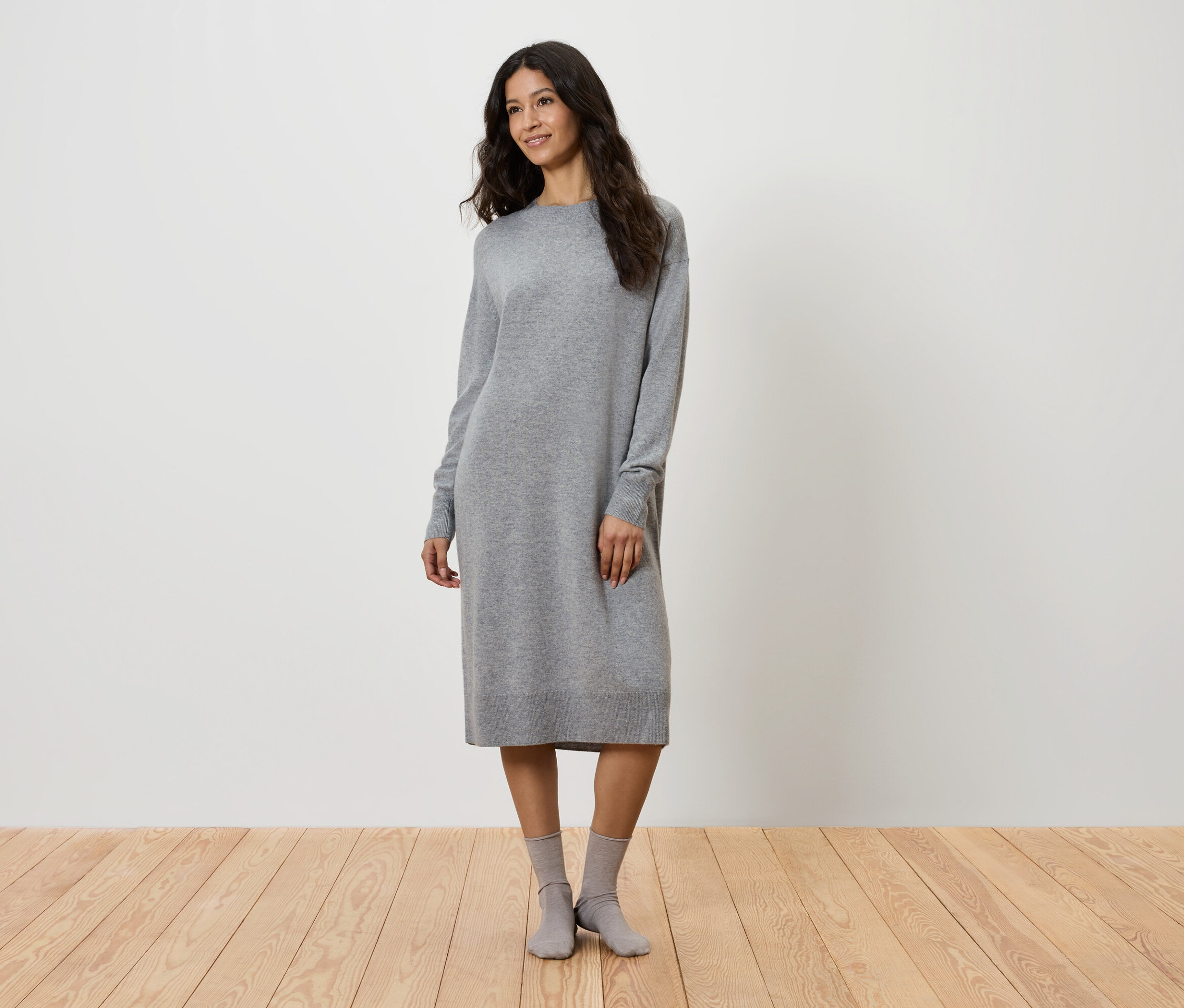 Une femme debout portant une robe grise en tricot et des chaussettes grises.