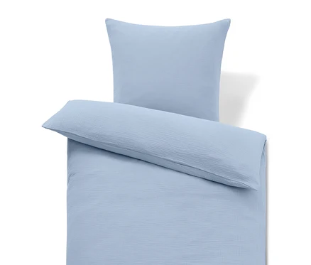 Literie bleu clair avec oreiller et coussin long.