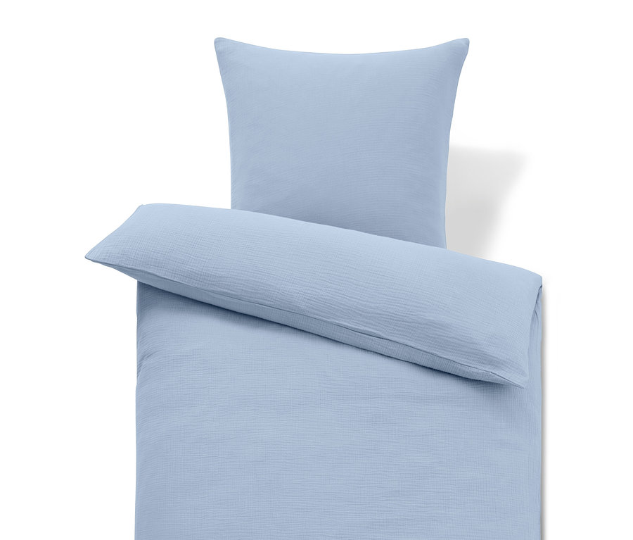 Literie bleu clair avec oreiller et coussin long.