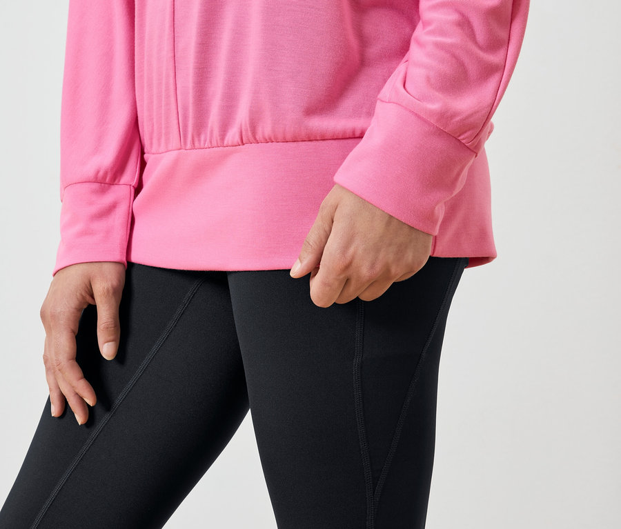 Gros plan d'une femme portant un sweat-shirt rose et un legging noir.