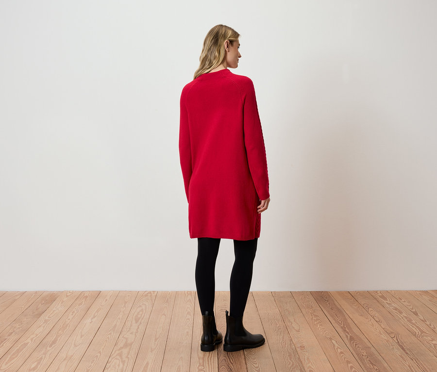 Une femme, vue de dos, porte une robe rouge, des leggings noirs et des bottes noires.