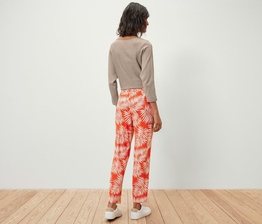 Femme debout de dos portant un pantalon en jersey imprimé et un haut.