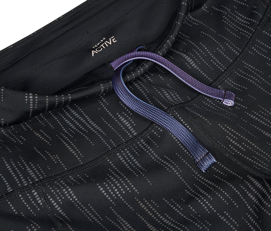 Gros plan sur un legging de sport noir et gris avec un cordon de serrage violet à la taille.