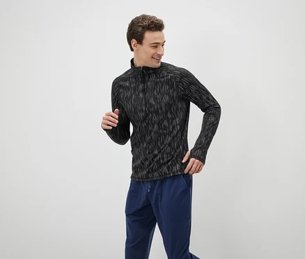 Homme portant un haut de sport noir à manches longues et un pantalon de survêtement bleu.