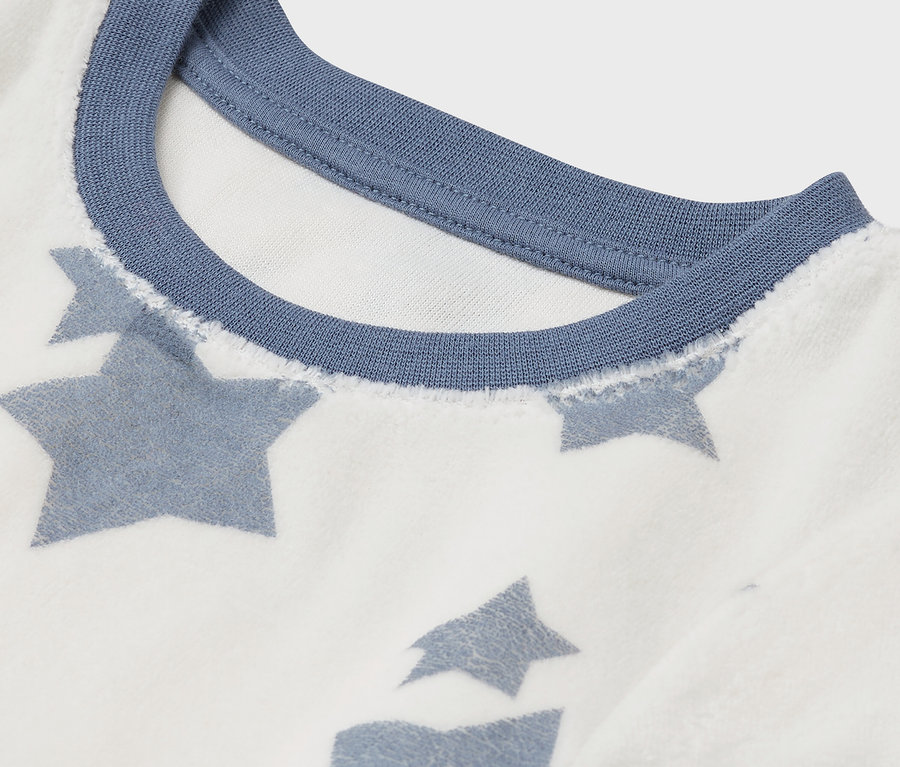 Gros plan d'un t-shirt blanc avec des étoiles bleues et une encolure bleue.