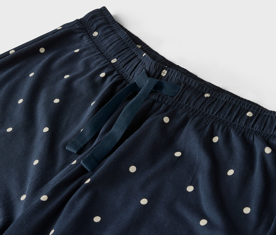 Détail d'un pantalon bleu marine à pois blancs, avec une taille élastique et un cordon de serrage.