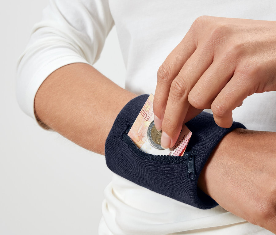 Une personne met une pièce d'un euro dans un bracelet de poignet bleu marine.