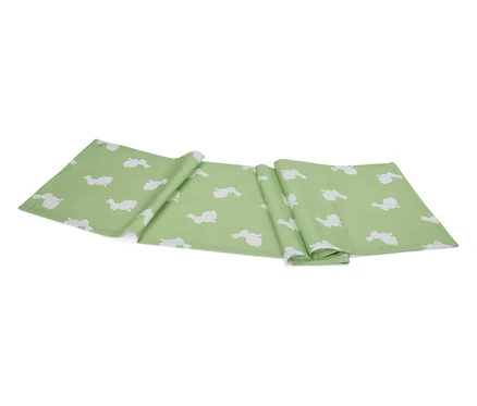 Un chemin de table vert clair avec un motif de lapins blancs est plié sur un fond blanc.