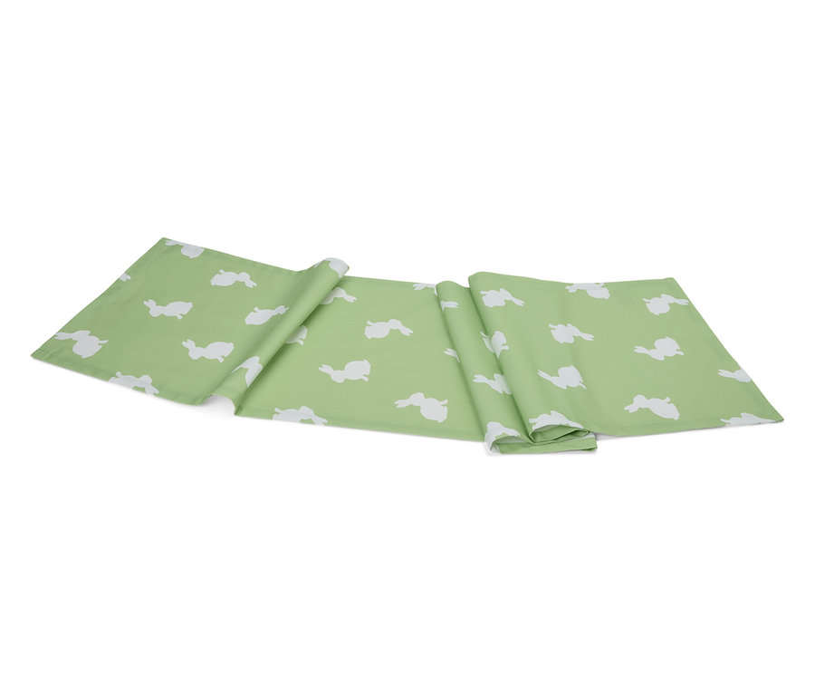 Un chemin de table vert clair avec un motif de lapins blancs est plié sur un fond blanc.