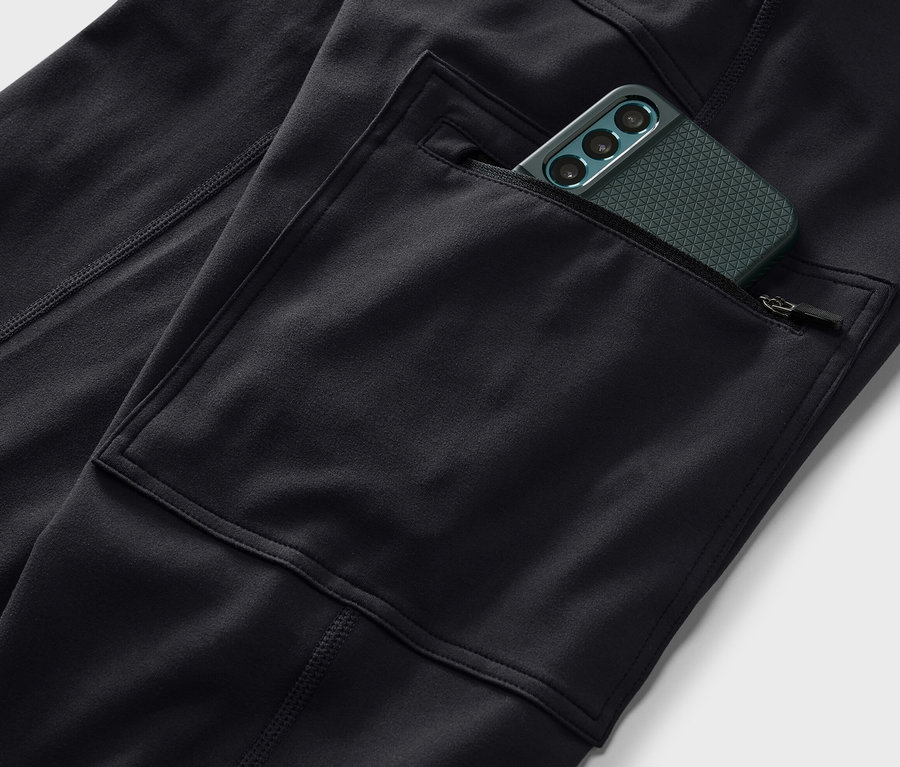 Gros plan sur un collant d’extérieur noir avec une poche contenant un téléphone portable vert.