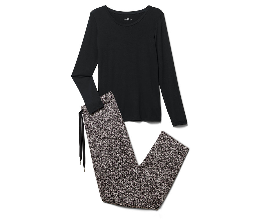 Un haut de pyjama noir à manches longues et un pantalon de pyjama à fleurs sont posés sur un fond blanc.