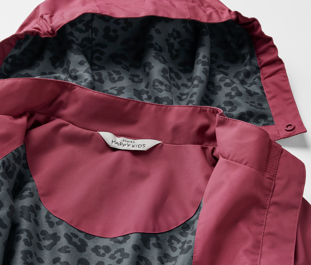 Gros plan sur une parka de pluie pour enfant avec capuche et motif léopard à l'intérieur.