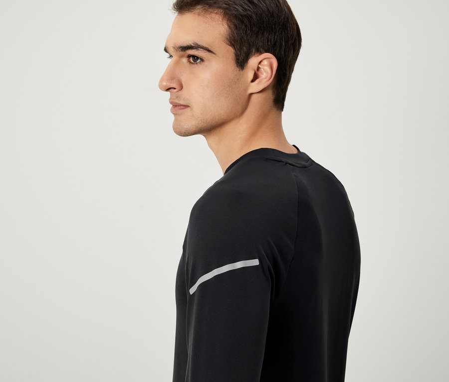 Homme de profil portant un t-shirt noir à manches longues avec une bande réfléchissante.