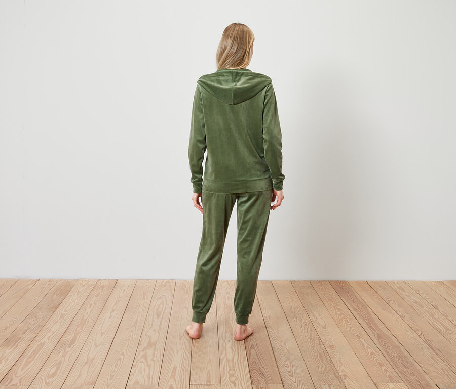 Une femme, vue de dos, porte un survêtement en velours vert olive.
