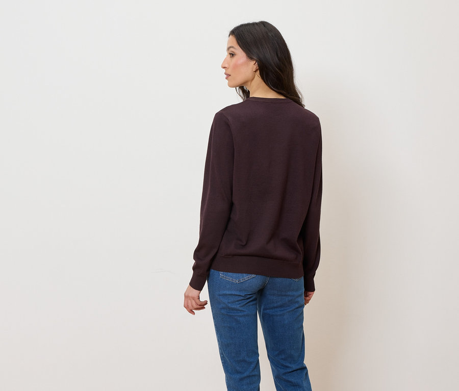 Femme portant un pull violet foncé et un jean bleu, vue de dos.