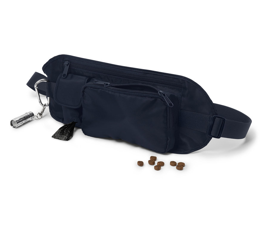 Une banane bleu foncé avec plusieurs poches, un sac à excréments, une lampe de poche et des croquettes pour chien sur fond blanc.