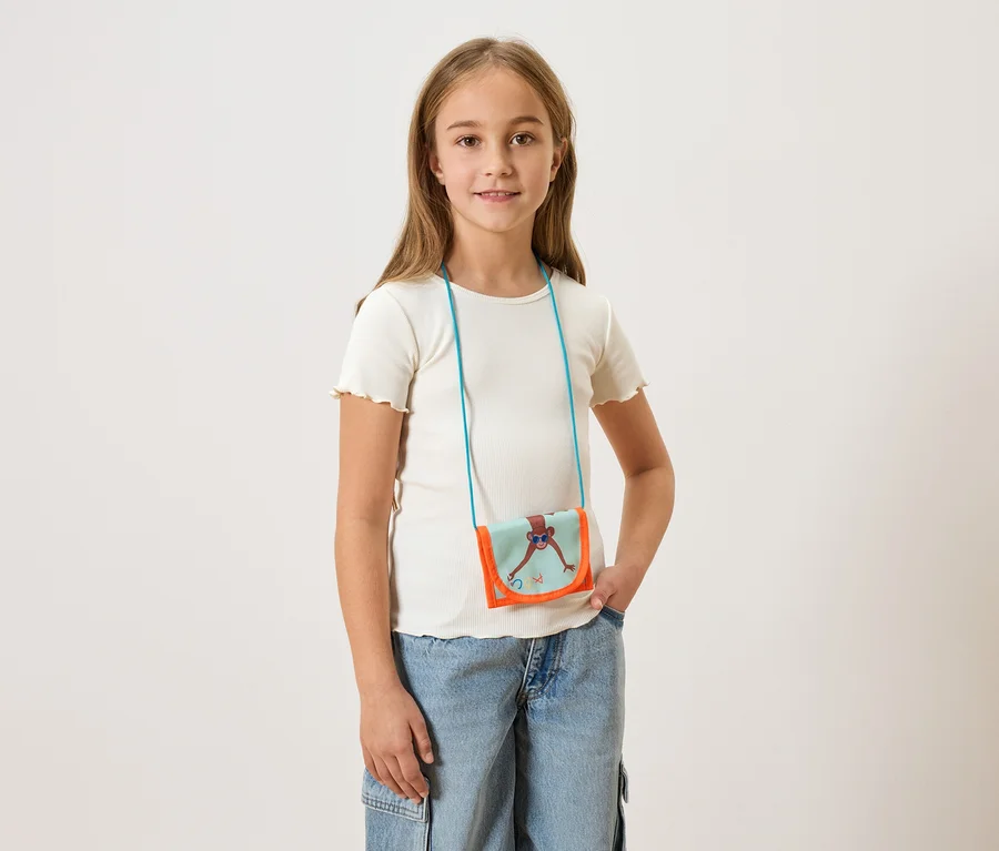 Fille portant un t-shirt clair et un jean, avec un petit sac à bandoulière avec un singe dessus.